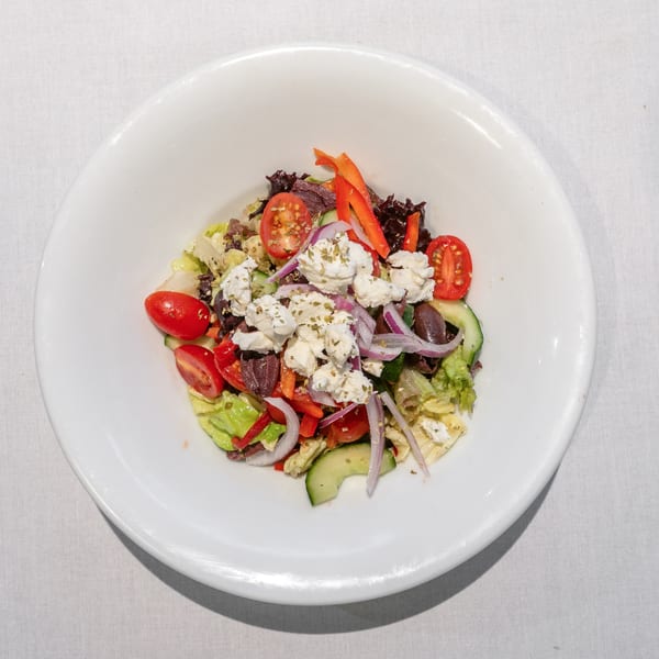 Greek salad with lettuce, tomatoes, cucumbers, red onions, bell peppers, olives, and feta cheese.